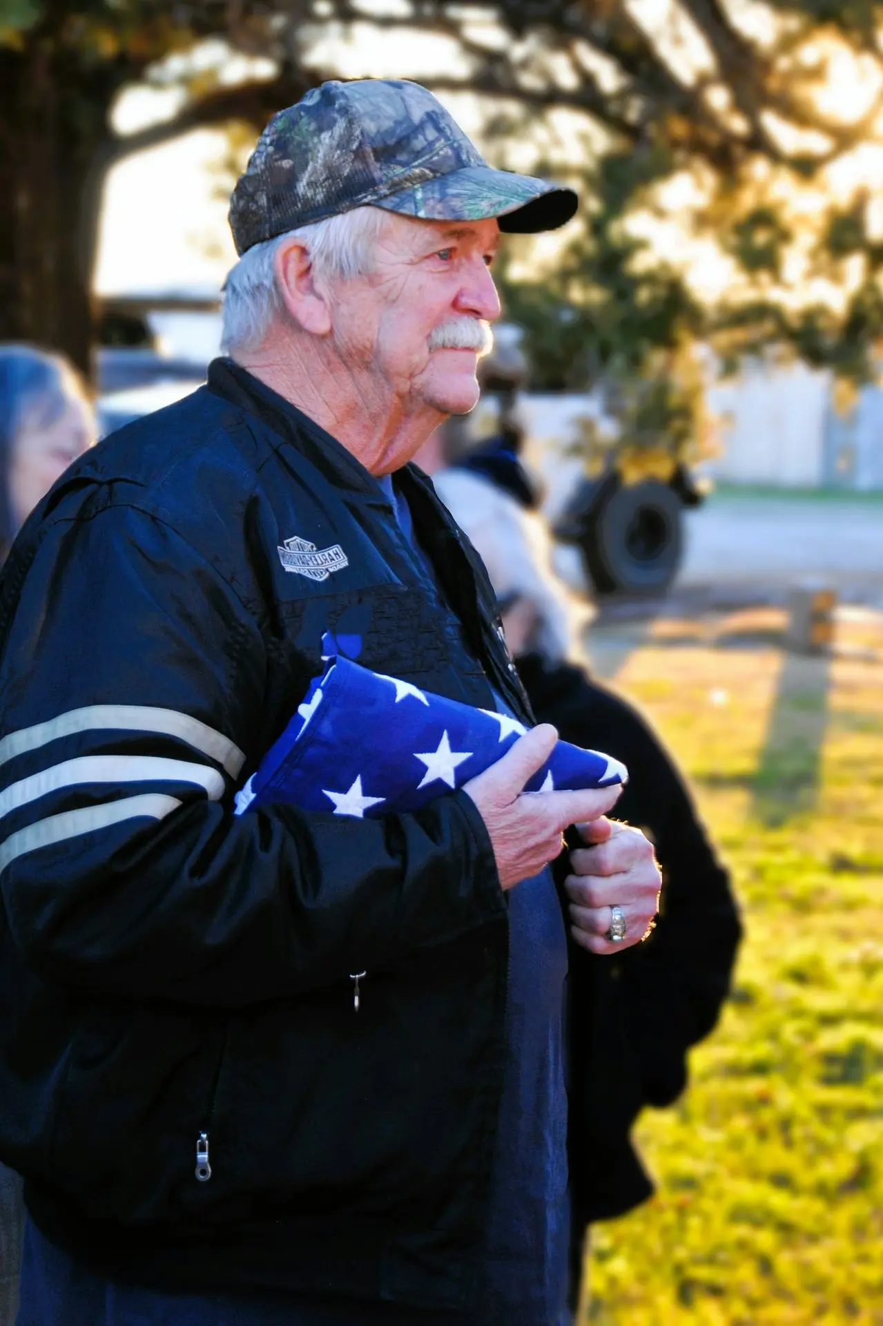 A man in a black jacket holding an american flag